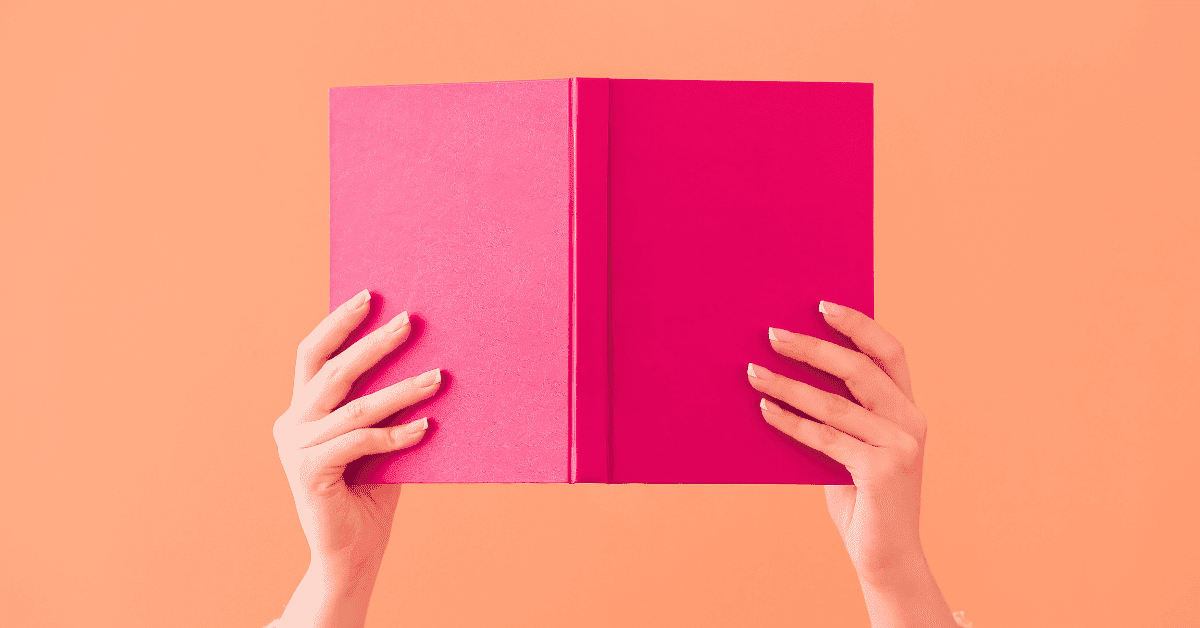 Hands holding up a pink book on an orange background to give contect to storytelling in content creation