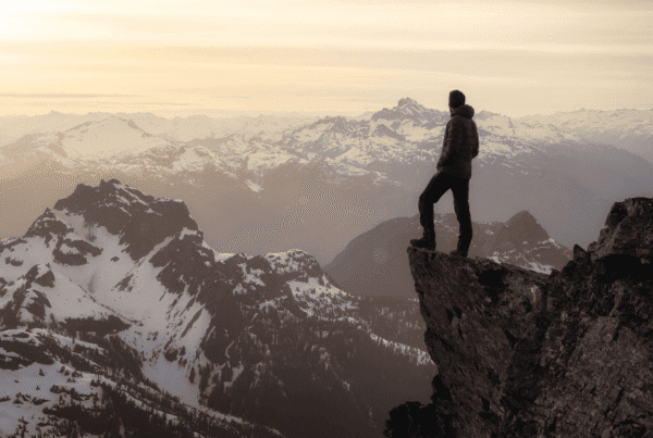 A man standing on the edge of a rock face looking out at mountains in front of him to symbolise digital marketing thought leadership