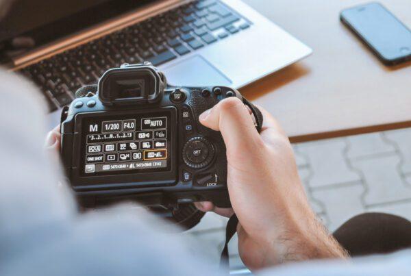 Repurposing content : man holding a camera looking and adjusting the menu settings.