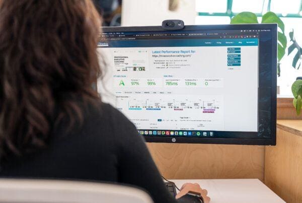 A web designer sits at a computer analysing a website performance report, illustrating how analytics can influence your decision to redesign your website.