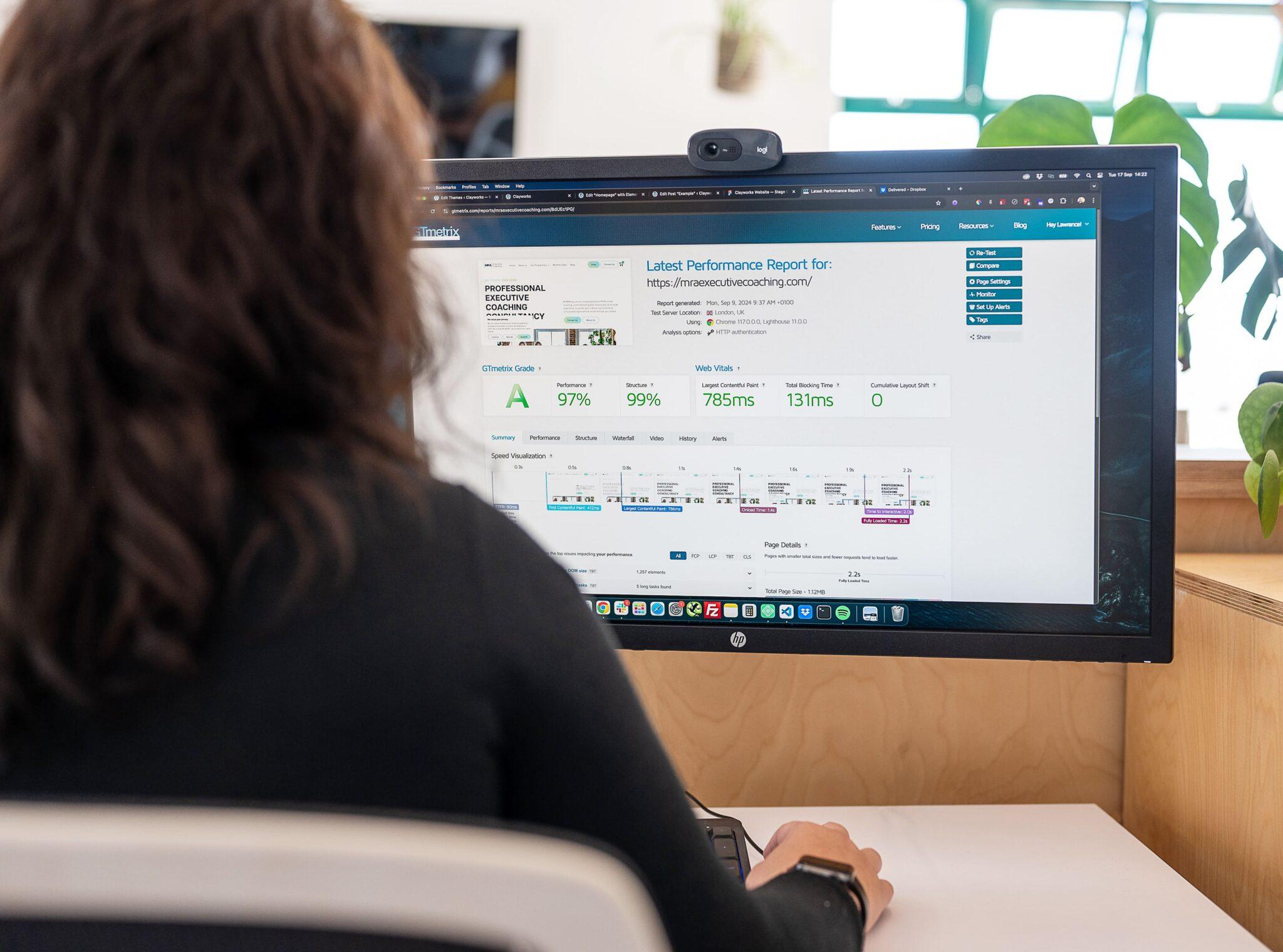 What Are Core Web Vitals and Why Do They Matter for Your Business? 1 A web designer sits at a computer analysing a website performance report, illustrating how analytics can influence your decision to redesign your website.