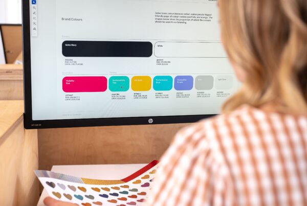 A woman sits at her desk looking at the brand colours for Solve Web Media deciding when to redesign your website