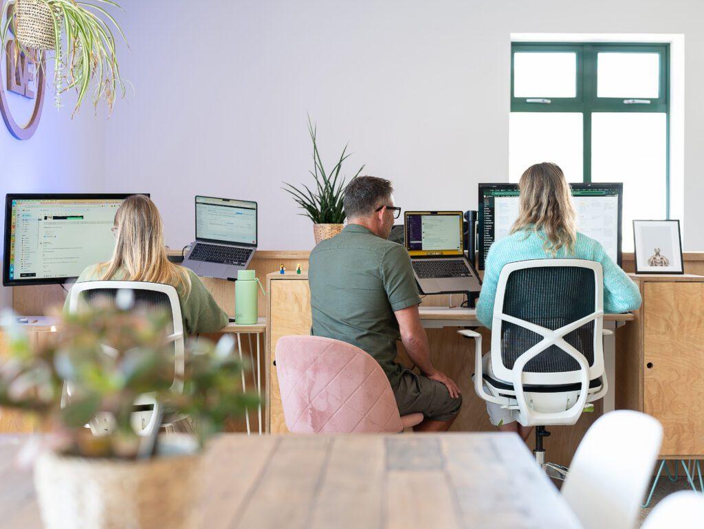 SEO Content Creation That Connects Users and Search Engines 3 Three people sat at desks in an eco friendly office, working through SEO content creation.