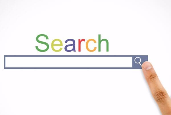 A finger pointing at a colourful search bar with the word "Search" displayed above it in multi-coloured letters, representing a traditional web search experience.