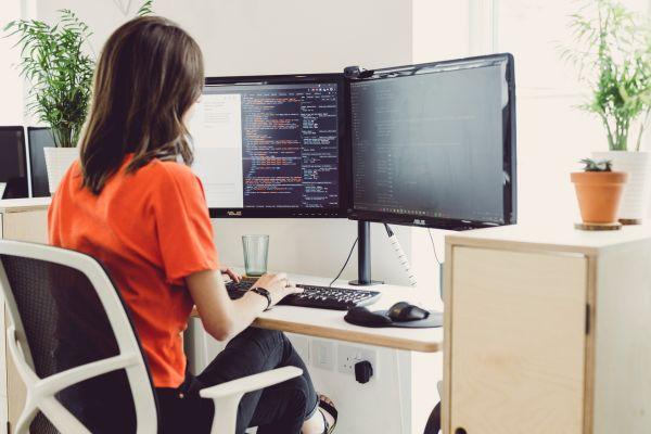 A female web designer, writing accessible code on a double-screen monitor in the Solve office.