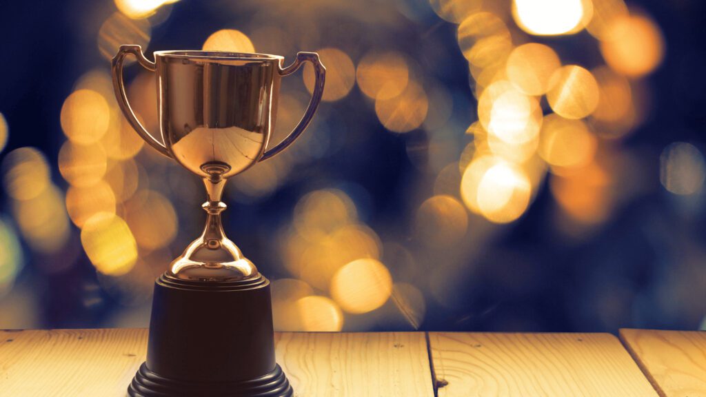 The Real Benefits of Entering Industry Awards 2 A trophy on a wooden table with bokeh lights in the background to represent an award ceremony
