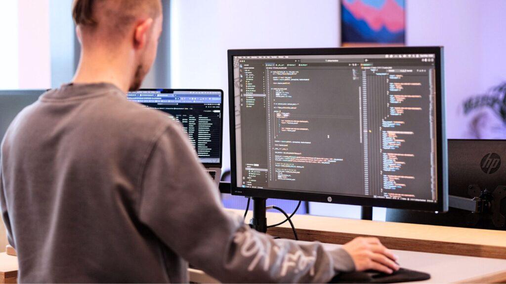 A man stands at a stand up desk, coding for custom website development