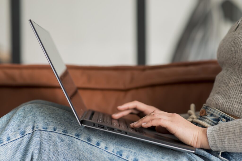 A woman lies on the sofa on her laptop on a terracotta sofa