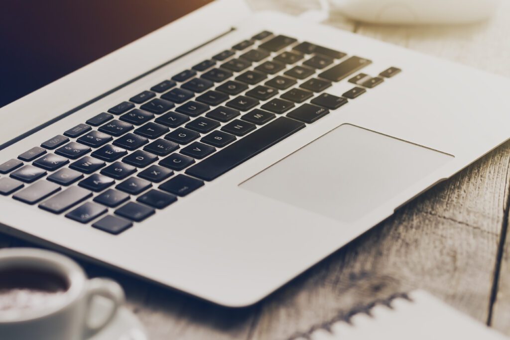 A laptop keyboard on a wooden desk with a cup of coffee. SEO for ai overviews toolkit