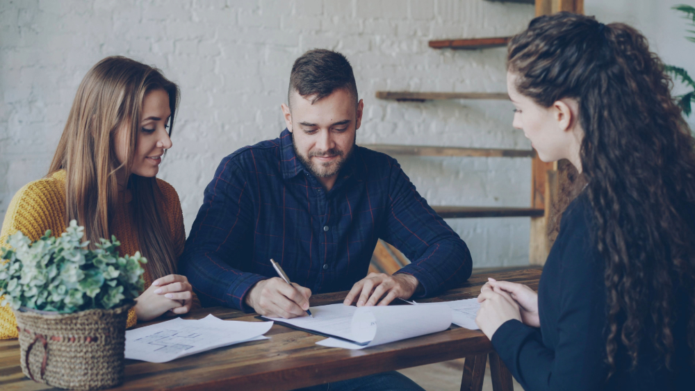 Two ladies and one male chatting around a table, with notepad and pen, discussing professional services website design.
