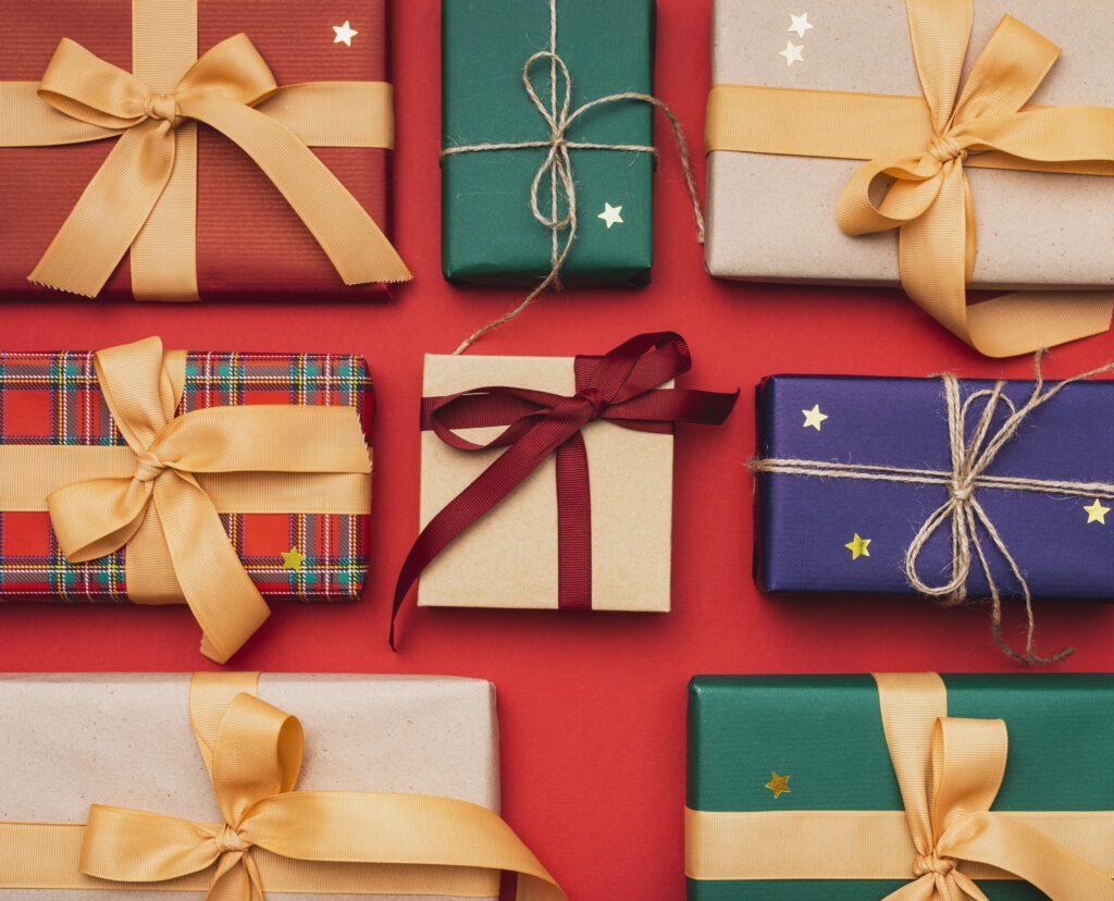 Presents laid out on a red background with different wrapping papers and ribbons