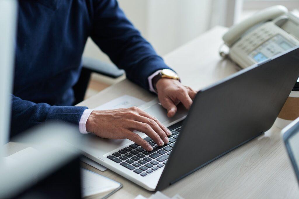 high angle view of a business man sat typing on a laptop in an office using a website that has been designed to be accessible