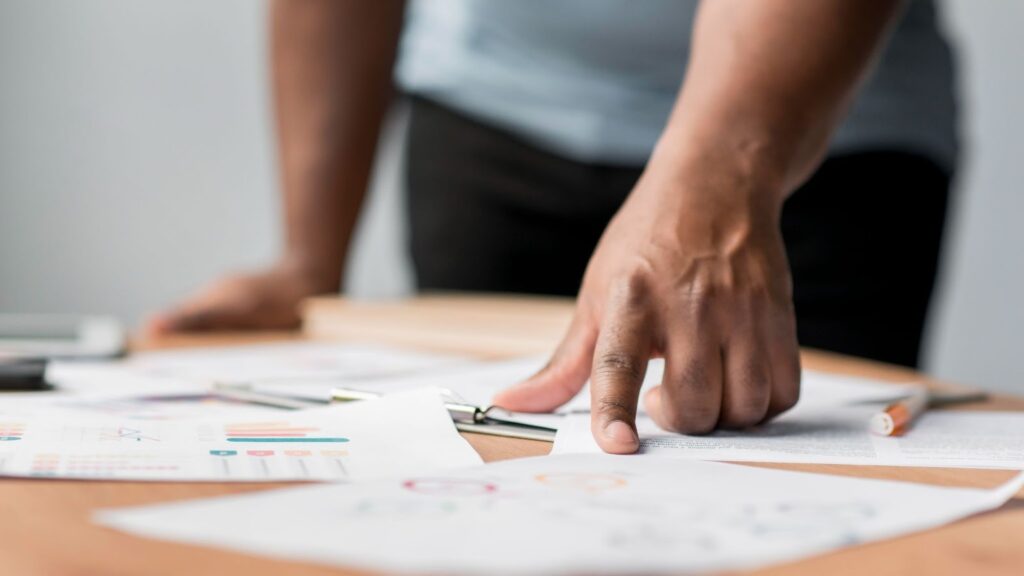 The Real Benefits of Entering Industry Awards 5 Man points at paper planning which industry awards to enter. Paper spread across a desk with scribbles and pencils.