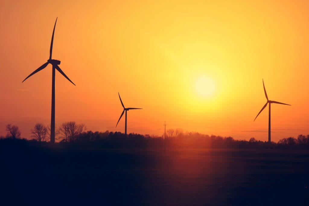 A sunset backdrop with renewable energy wind turbines in the foreground