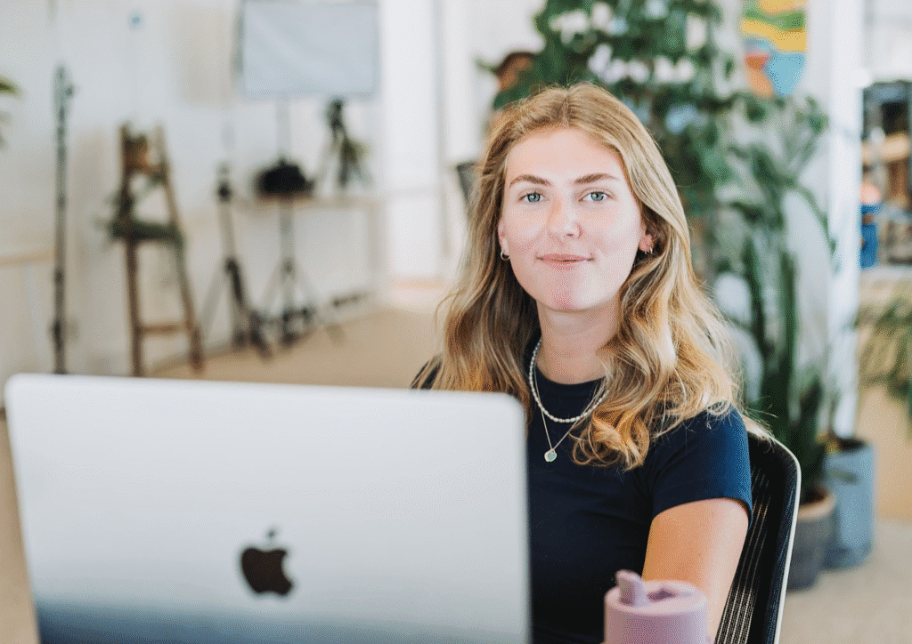 girl sat at her computer looking into the camera smiling