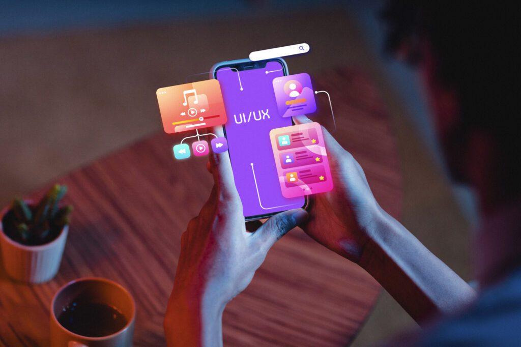 An over the shoulder shot of a man on his phone with the screen showing "UI/UX" and graphics coming out of the screen like music and notifcations.