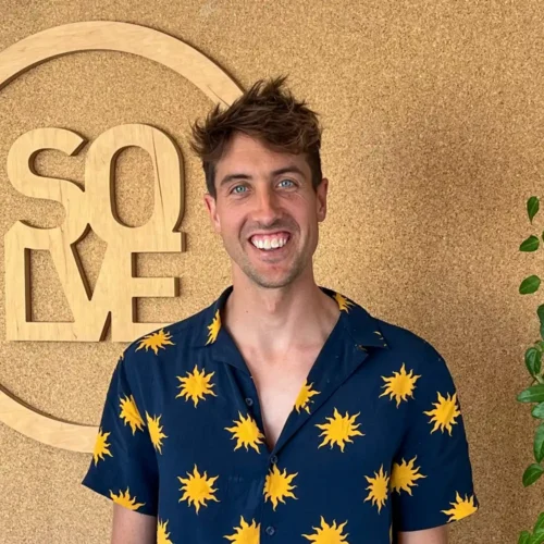 a man smiling in front of a sign