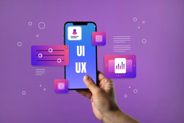 A hand holds a phone with the words "UX UI" on the screen against a purple background. Phone icons float around the phone.
