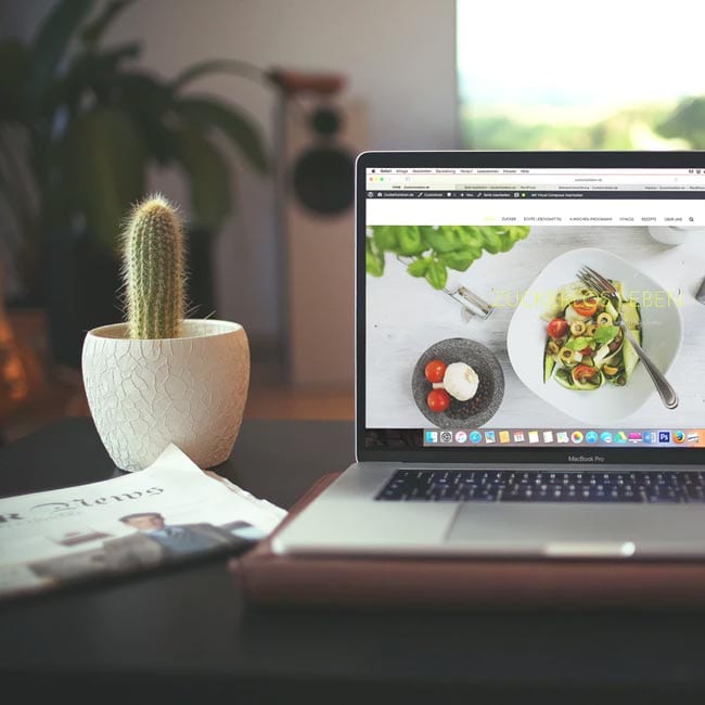 computed with salad picture holder on a dining table, next to the computer is a cacti 